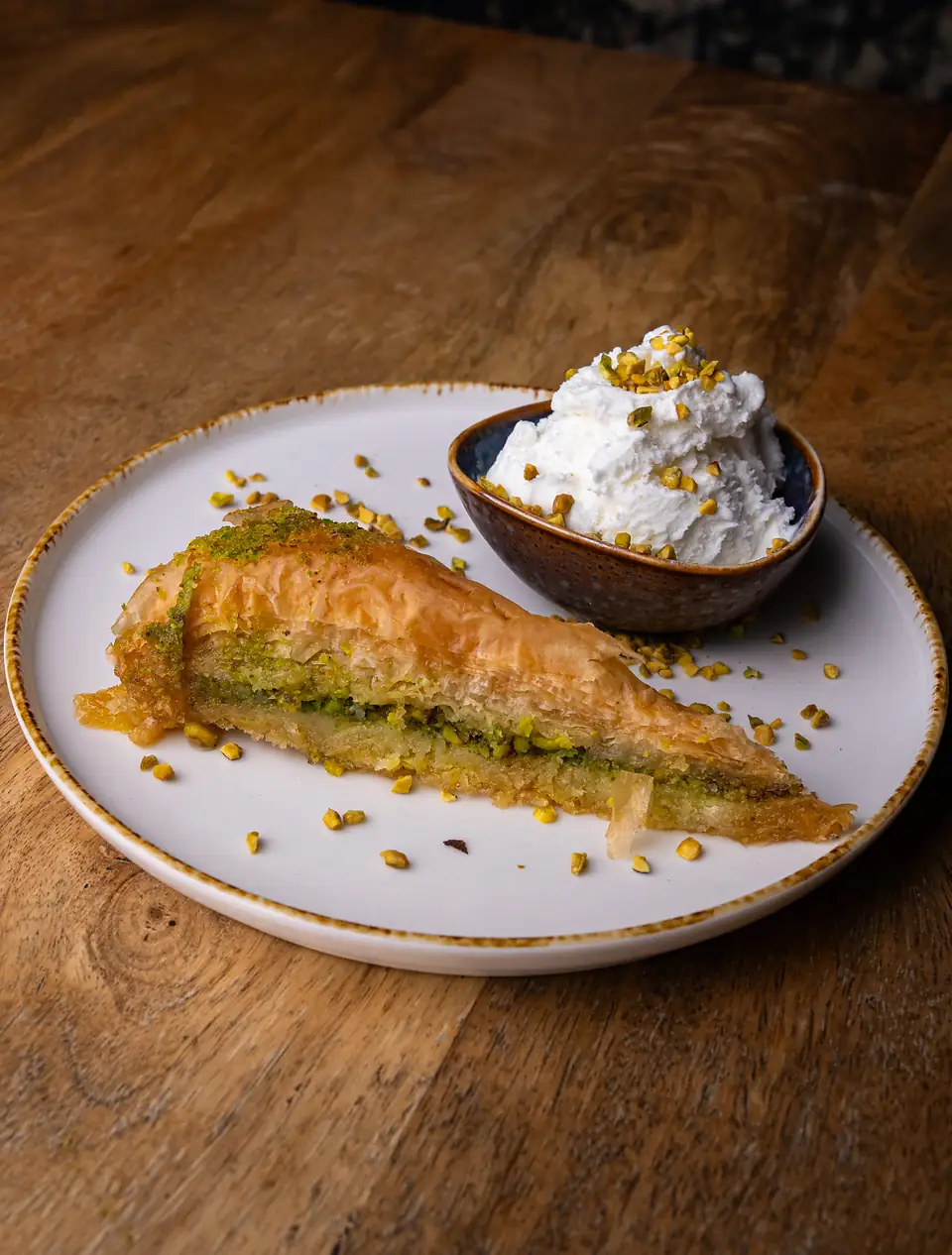 Pistacjowa baklawa havuç dilimi z miseczką lodów śmietankowych posypanych pistacjami.