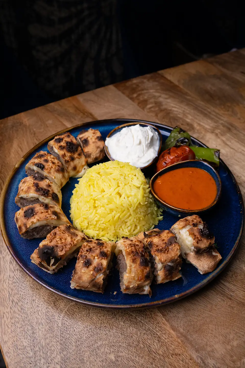 Beyti sarma: grillowane mięso jagnięco-wołowe zawinięte w ciasto, pokrojone w plastry, z ryżem, jogurtem i sosem pomidorowym.